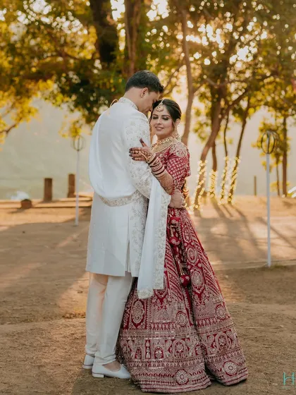 A sundowner wedding in the hills of Jim Corbett. The golden light filtering through the trees creates a magical, romantic glow around the couple in their stunning wedding attire.