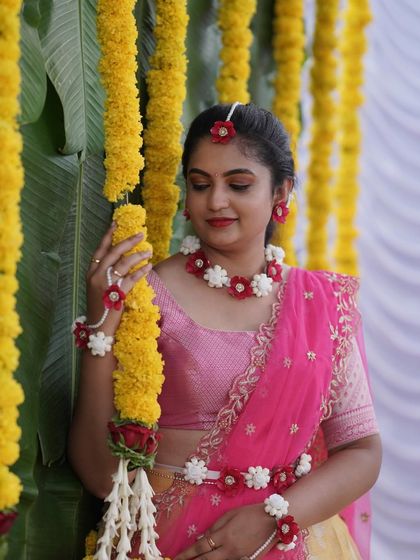 A close-up of the bride's floral jewelry and the marigold garland backdrop, highlighting the small details that make a Haldi ceremony special.