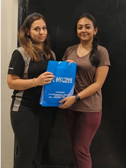 A trainer and member pose with an anniversary gift. We cherish the long-term relationships we build with our community.