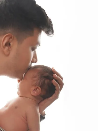 A father's gentle kiss on his newborn's forehead. This high-key, minimalist photo is powerful in its simplicity, showing the profound bond between a parent and child.
