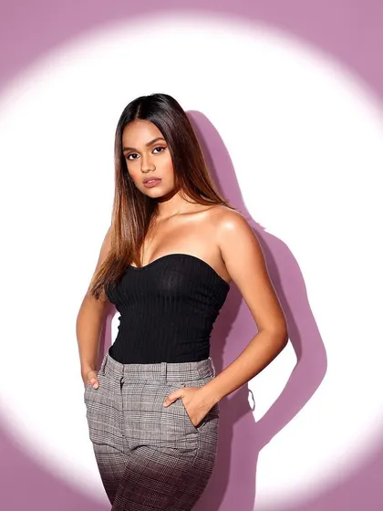 A model posing in a spotlight against a lavender background, a classic technique for creating clean, focused fashion portraits.