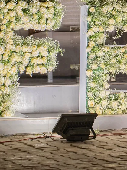 A massive floral installation spelling out the brand name 'FENNEL' in white roses and baby's breath, creating a huge impact for a corporate anniversary.