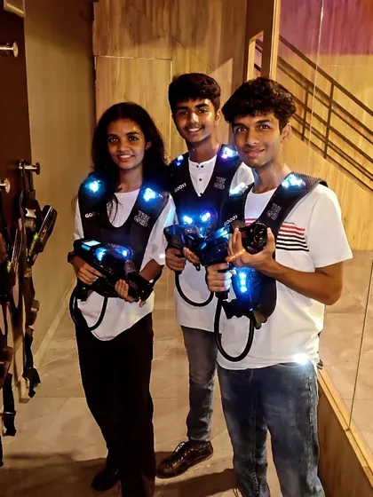 Three friends pose with their laser tag gear, ready for an exciting game.