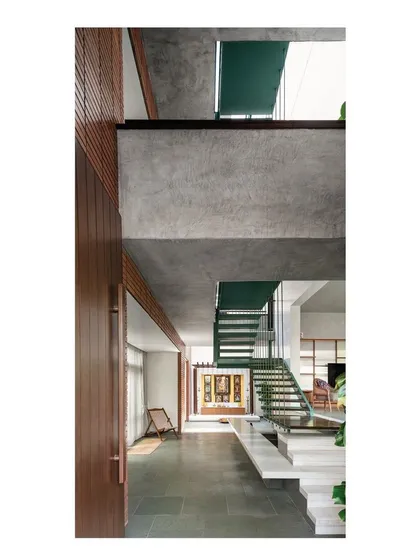 This view showcases the vertical circulation core, where a multi-level staircase of steel and wood connects the floors. The design emphasizes volume and transparency, with sightlines extending through the house to create a feeling of an interconnected, singular space.
