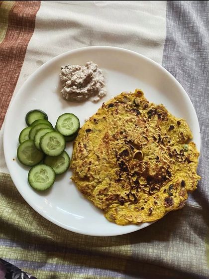 A besan cheela served with cucumber slices and a side of chutney. This is a favorite among clients for a quick and healthy breakfast.