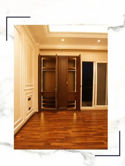 This bedroom showcases our beautiful wooden flooring and a large, dark wood wardrobe that provides ample storage. The room opens onto a balcony, filling the space with natural light.