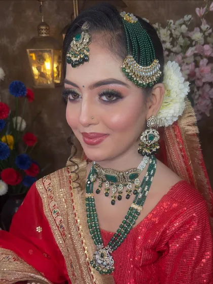 A close-up of the exquisite jewellery. The green beaded passa and maang tikka are paired with a matching choker and a longer necklace, creating a layered and royal effect.