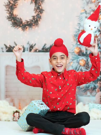 A joyful portrait of a young boy celebrating Christmas in our studio. The festive red shirt and snowman prop add to the holiday spirit.