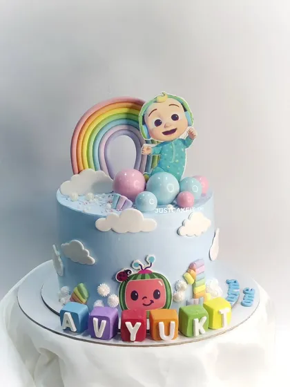 This elegant Cocomelon theme cake features pastel colors and cute, edible details like the character blocks. It was paired with matching rainbow cupcakes for a complete party set.
