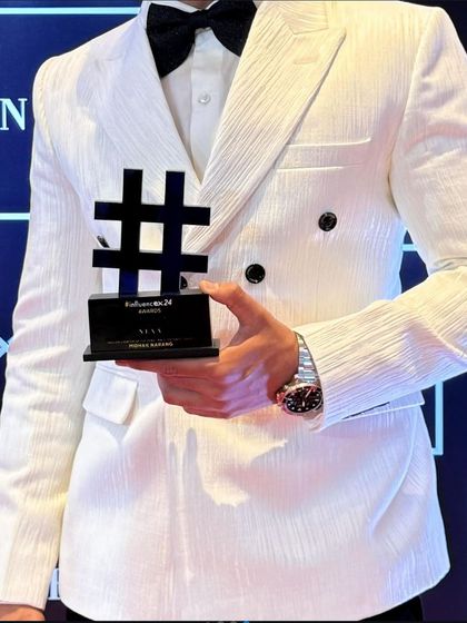 A close-up of the award-winning look. The textured white fabric of the blazer, paired with a classic black bow tie, showcases a modern take on formal black-tie dressing.