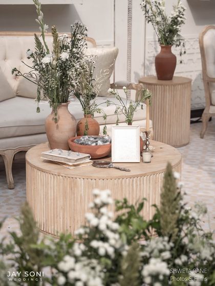 A close-up of a coffee table in the ivory lounge, styled with rustic vases, wildflowers, books, and other curated objects to create a lived-in, elegant feel.