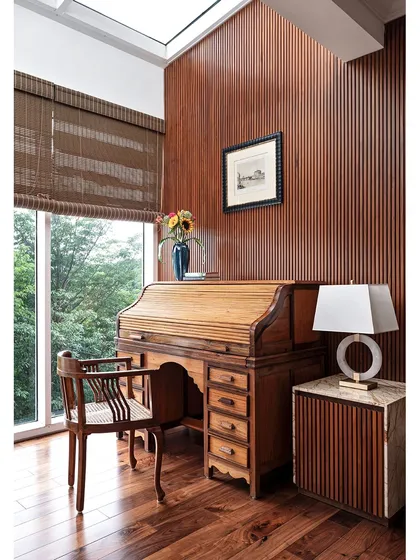 We love creating spaces that reflect our clients' passions. This private study, with its rich hardwood flooring, fluted wall paneling, and antique roll-top desk, was designed to feel like a classic English study, filled with natural light from a skylight.
