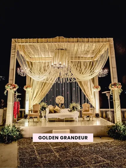 We call this design 'Golden Grandeur'. The stage features a magnificent canopy of draped fabric and multiple crystal chandeliers, creating an opulent and royal setting for a truly luxurious wedding.