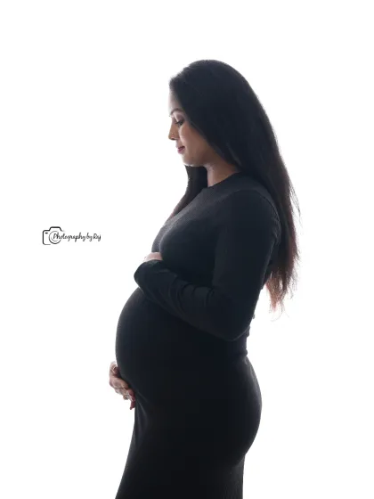 A classic silhouette portrait of a mother-to-be in a simple black dress against a white background.
