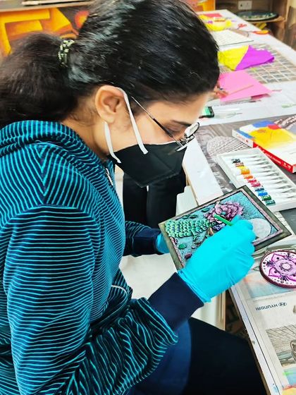A student wearing gloves and a mask while working on her relief art, demonstrating the professional and safe practices we maintain in our studio.