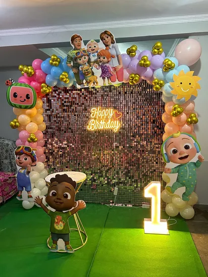 Another view of the Cocomelon first birthday, showing the full setup with the shimmer wall and green turf floor.