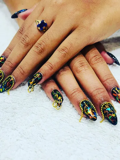 An edgy and unique design featuring black glass-effect nails with colorful foil inside, complete with gold chain and ring piercings.