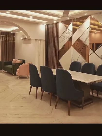 This image shows the dining area adjacent to the living room from our quick renovation project, tied together by a striking geometric wall panel of marble and mirror.