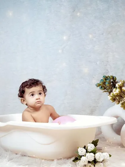 A simple and sweet bath time shoot for a sitter session, with the baby in a small tub against a sparkling backdrop.