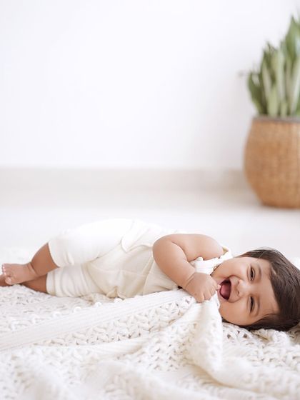 A baby laughing while playing with a soft blanket.