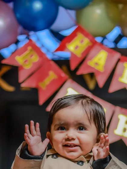 A happy wave from the birthday boy! This candid shot captures the excitement and joy of a little one surrounded by balloons and birthday banners.