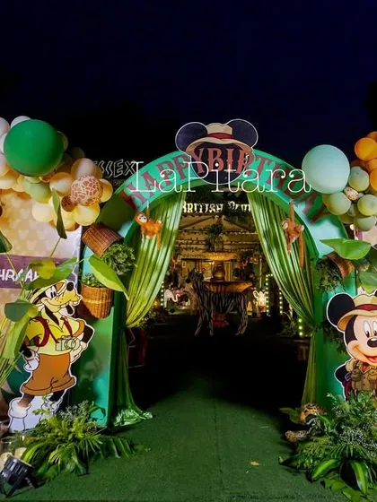 Adventure awaits at this Mickey Mouse jungle safari entrance. As night falls, the lighting brings the entire scene to life, highlighting the vibrant balloon arch, playful character cutouts, and lush greenery. This setup shows how I create an exciting and immersive atmosphere that captivates guests of all ages.