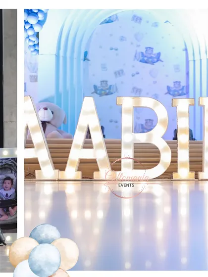 Large, illuminated marquee letters spelling out the birthday boy's name, "AABI," for his first birthday party. This photo highlights my custom lighting and decor options for children's events, set against a soft blue, teddy-bear-themed backdrop.