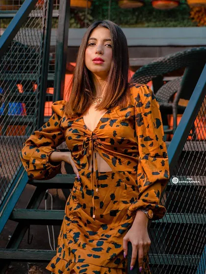 A direct and confident pose from the same series, highlighting the model's outfit and the interesting textures of the location.