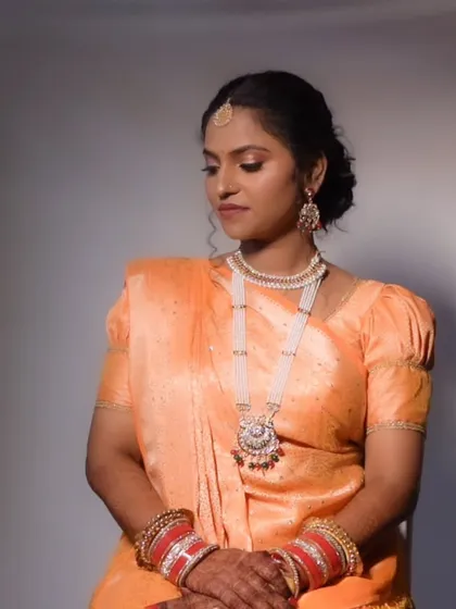 A portrait of the bride in her orange wedding saree, looking serene and beautiful.