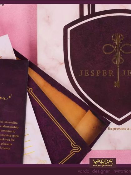 A close-up view of a luxury corporate invitation for a jewelry brand. This shot highlights the fine details, from the gold foil key logo on the shield to the rich, textured paper, showcasing the premium craftsmanship involved.