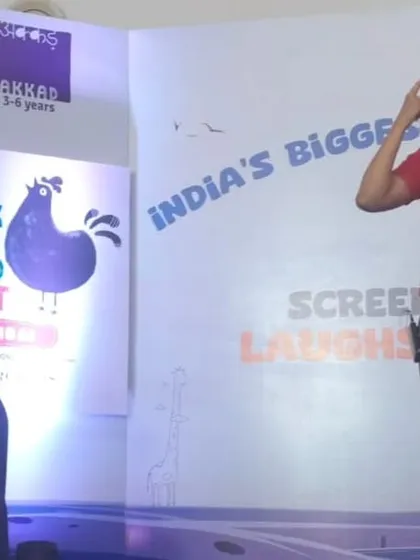 Here I am on stage, wearing a fun character hat and speaking to the audience. We always involve the children in our stories, asking them questions and inviting them to participate, making it an interactive experience for everyone.