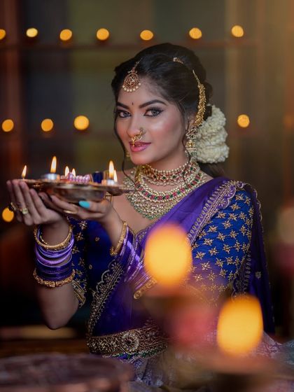 A beautiful close-up with diyas, highlighting the warm glow of the antique gold jewellery.