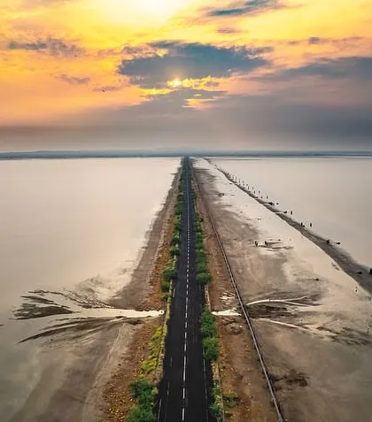 The road to Dholavira, a UNESCO World Heritage site in the Rann of Kutch, appears like a lifeline through the salt marsh. This aerial shot reveals the abstract patterns and immense scale of this unique landscape.