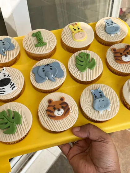 These jungle animal cupcakes were part of a first birthday dessert table. Each cupcake has a unique, handcrafted fondant topper, including elephants, tigers, zebras, and giraffes on a wood grain patterned base.