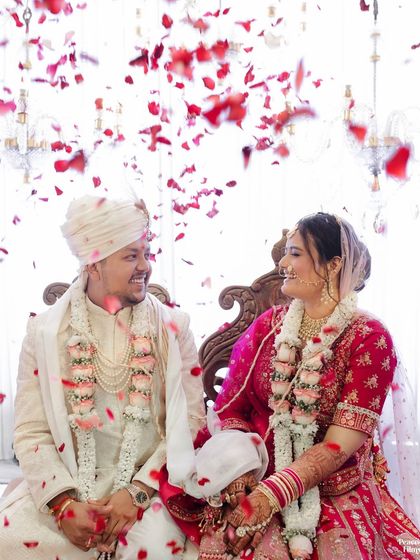 A shower of rose petals rains down on the happy couple. This joyful moment from their wedding ceremony is full of color, emotion, and celebration.