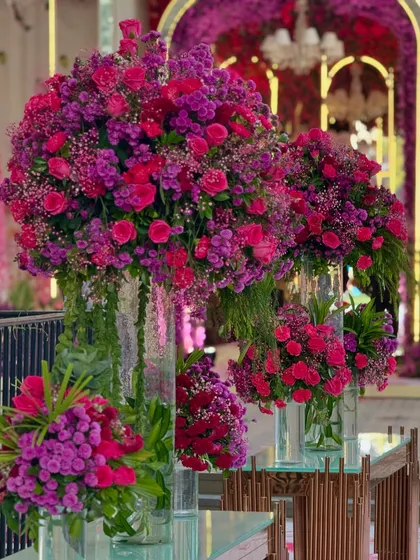 A close-up of a floral arrangement in a tall glass vase. The bold hues of the flowers add a pop of color and life to every corner of the venue.