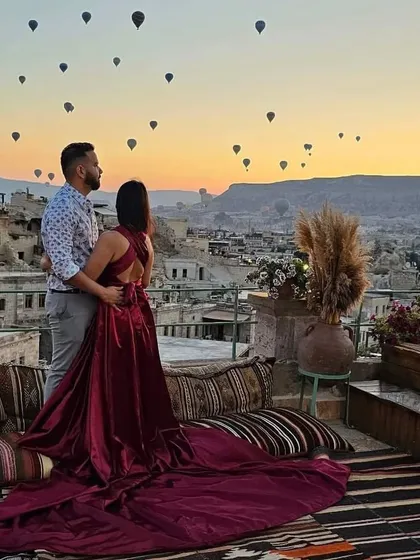 The couple looking out at the sunrise and hot air balloons in Cappadocia, a perfect moment captured with the bride in my elegant trail gown.