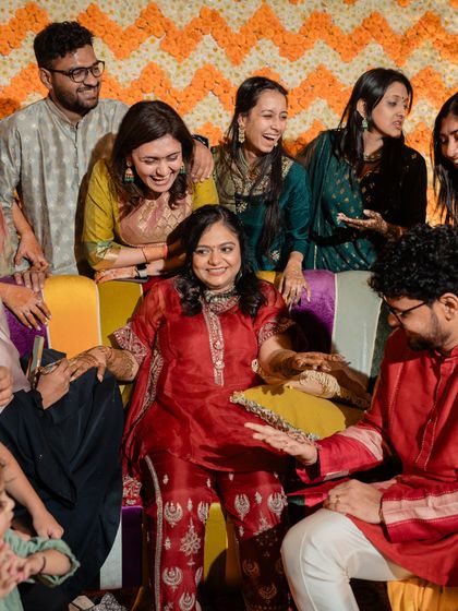 The bride surrounded by her family and friends at her mehendi. Her relaxed red outfit and minimal glam look allowed her to be the center of attention while feeling completely at ease.