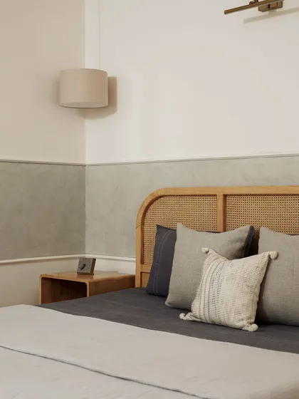 This bedroom embodies the essence of Japandi design, blending the simplicity of Japanese minimalism with Scandinavian warmth. The rattan headboard, textured lime-wash wall, and soft, neutral bedding come together to create a sanctuary of calm.