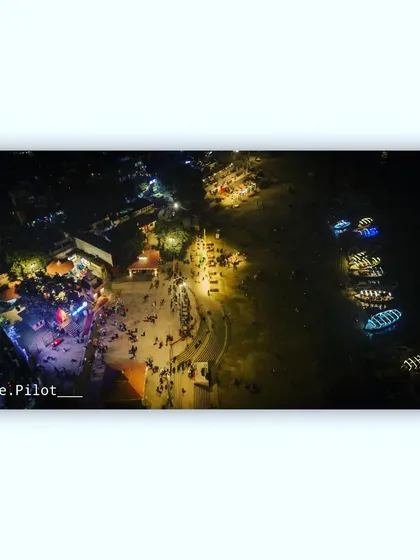An overhead view of the bustling Assi Ghat in Varanasi at night, showing people and boats along the river Ganga.