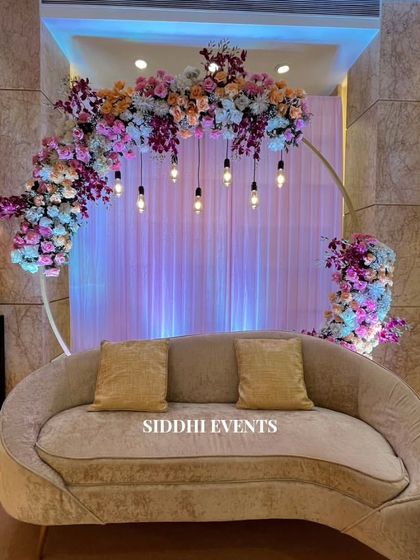 A closer look at the floral ring backdrop, showing the beautiful blend of pastel flowers and the warm glow from the hanging lights, perfect for an intimate celebration.