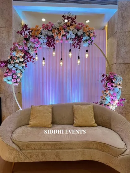 A closer look at the floral ring backdrop, showing the beautiful blend of pastel flowers and the warm glow from the hanging lights, perfect for an intimate celebration.