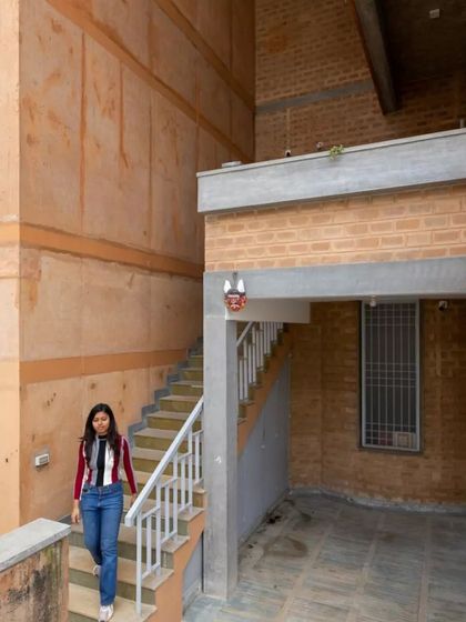 The staircase and courtyard of Radhika and Manoj's house in Bangalore. The high wall on the left is made from 'mud concrete', a technique where we reuse demolition debris as aggregate, turning waste from the old building into a resource for the new one.