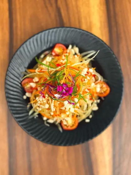 A top-down view of our classic Thai Som Tam salad, a refreshing mix of raw papaya, carrots, tomatoes, and peanuts from the 'Bangkok Joes' menu.