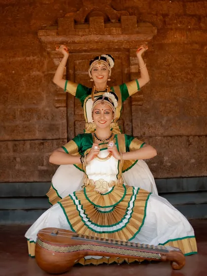 A portrait of two dancers in a classic Mohiniyattam pose. The composition highlights their grace and the beauty of their traditional attire.
