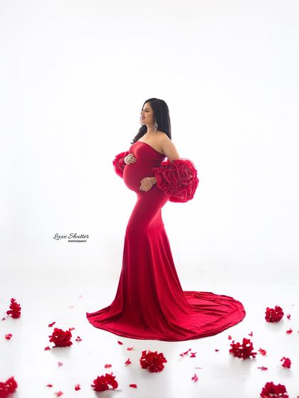 A classic profile pose in a stunning red gown, surrounded by delicate petals. This composition is both romantic and powerful, focusing on the beauty of the pregnancy journey.