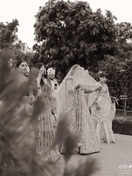 A black and white photo of the bride's procession, captured from a distance to show the entire group.