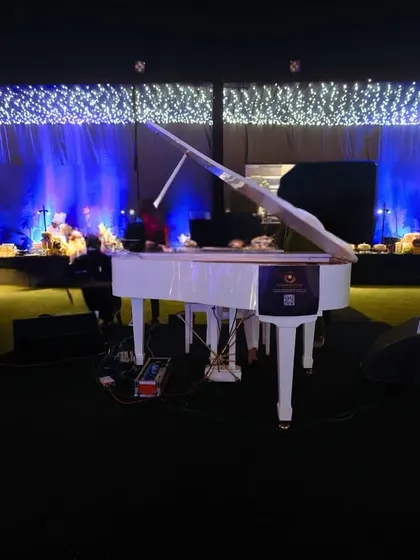 A classic white grand piano on stage, set against a backdrop of deep blue light and a ceiling of twinkling fairy lights, created a focal point of pure elegance and melody.