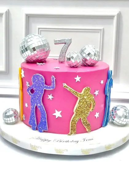Get ready to dance with this vibrant disco-themed birthday cake. The bright pink tier is decorated with glittery disco dancers, stars, and topped with shiny disco balls for a fun, retro party vibe.