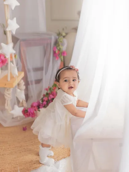 Pulling up to stand is a huge milestone. This little girl proudly holds onto the bench, giving us a peek at her determined and sweet personality.